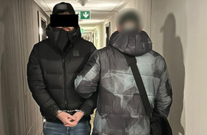 policjant prowadzi zatrzymanego.