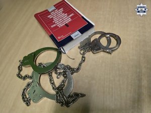 Kodeks karny i postępowania karnego a obok leżą kajdanki zespolone.