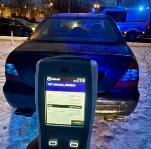 Na pierwszym planie trzymany tester narkotykowy, w głębi samochód, którym kierował zatrzymany 44-latek.