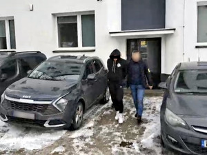 Policjant prowadzi zatrzymanego.