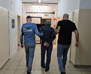 Policjanci prowadzą zatrzymanego do aresztu.