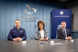 Komendant Główny Policji siedzi obok kobiety i mężczyzny z Totalizatora Sportowego.