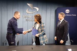 Komendant Główny Policji podaje rękę kobiecie z Totalizatora Sportowego.