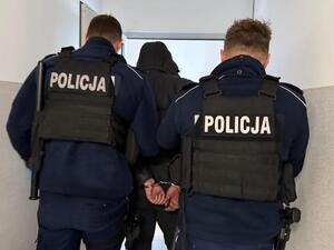 Dwaj policjanci prowadzą zatrzymanego.