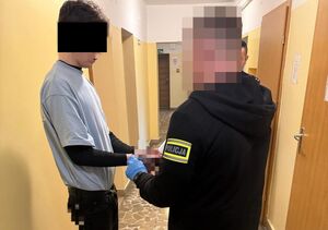 Funkcjonariusz zakłada kajdanki zatrzymanemu.