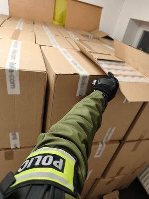 Policjant wskazuje zabezpieczone papierosy.