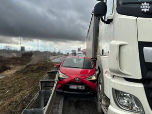 Samochód osobowy między barierą a samochodem ciężarowym na autostradzie.