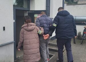 Zatrzymany prowadzony w kajdanowych przez funkcjonariuszy.