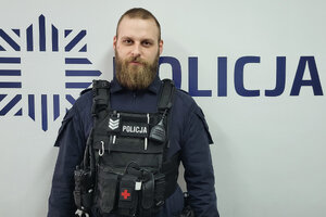 Policjant stoi na tle napisu Policja.