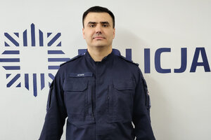 Policjant stoi na tle napisu Policja.