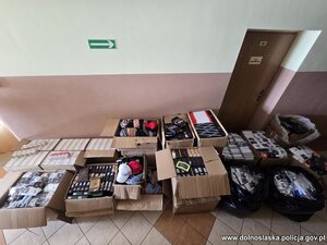 na podłodze rozłożone są kartony i worki z nielegalnym tytoniem, papierosami i odzieżą.