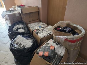 na podłodze rozłożone są kartony i worki z nielegalnym tytoniem, papierosami i odzieżą.