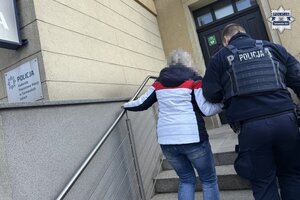 policjant prowadzi kobietę.
