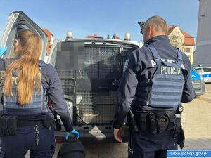 Dwaj policjanci przy radiowozie.