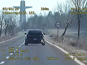 Stopklatka z nagrania wideorejestratora przedstawia pojazd jadący drogą przekraczający prędkość.
