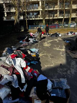 ubrania, torby porozkładane na ziemi. policjanci przeglądają towary.