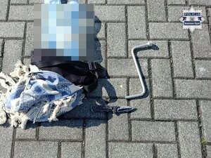 Mężczyzna skuty kajdankami, stoi przy ścianie.