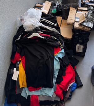 bluzki, kurtki, czapki i torby porozkładane na podłodze i w kartonach.