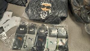 bluzki, kurtki, czapki i torby porozkładane na podłodze i w kartonach.