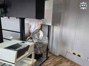 Policjanci prowadzą zatrzymanego. Pobierają odciski palców. pieniądze rozłożone na stole.