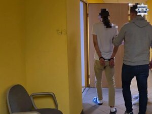 Policjanci prowadzą zatrzymanego. Pobierają odciski palców. pieniądze rozłożone na stole.