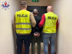 policjanci prowadzą skutego kajdankami mężczyznę.