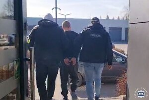 dwóch policjantów prowadzi zatrzymanego.