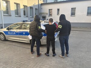 dwóch policjantów stoi z zatrzymanym.