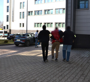 Dwaj policjanci prowadzą zatrzymanego.