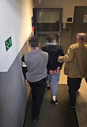 Dwaj policjanci prowadzą zatrzymanego.