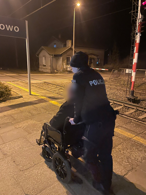 Policjantka pcha wózek inwalidzki z osobą.