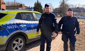 Policjanci stoją przy radiowozie.