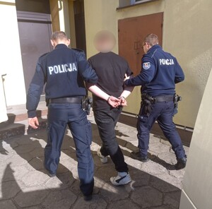 policjanci prowadzą zatrzymanego.