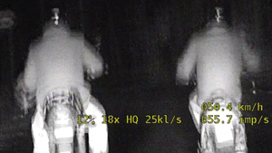 dwóch motocyklistów jedzie, widać tył ich motocykli i pleców.