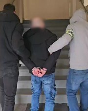 Dwaj policjanci prowadzą zatrzymanego.
