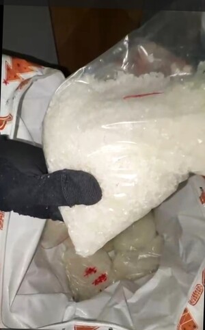 Trzymany w ręku worek z biała substancją.