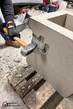 policjant uderza młotem w beton, w którym są schowane narkotyki.