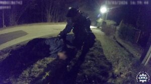 Policjnant podczas udzielania pomocy mężczyźnie leżącemu na ziemi.
