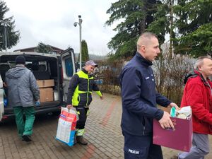nadkomisarz Tomasz Manuszewski niosący dary razem z pracownikami schroniska.
