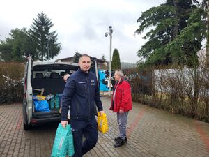 nadkomisarz Tomasz Manuszewski niosący dary razem z pracownikami schroniska.