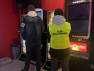 policjant i funkcjonariusz służby celno-skarbowej stoją obok automatów do gier.