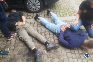 Zatrzymani leżą na ziemi.