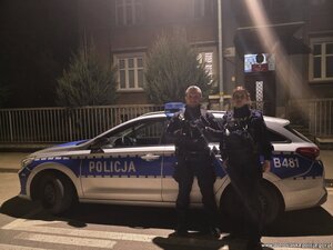 Pora nocna - dwoje policjantów przed radiowozem.
