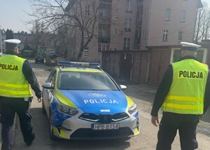 dwóch policjantów stoi przy radiowozie.