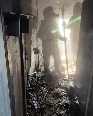 Dwaj strażacy w mieszkaniu gdzie wybuchł pożar.