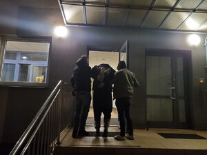 Dwaj policjanci wprowadzają do budynku zatrzymanego.