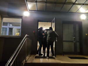 Dwaj policjanci wprowadzają do budynku zatrzymanego.