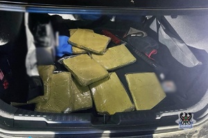 Noc. policjanci podczas kontroli drogowej przeszukują bagażnik. Żółte paczki.