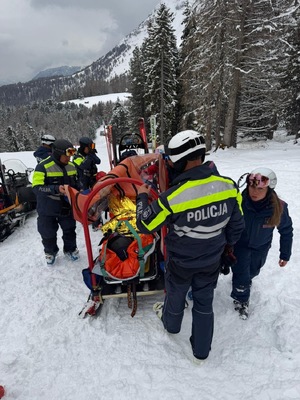 policjanci pomagają znieść poszkodowanego na noszach.