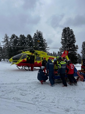 śmigłowiec ratowników medycznych. z przodu policjanci i ratownicy z poszkodowanym.